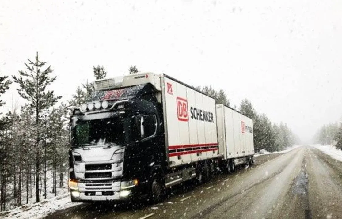 Scania med ekipage kör genom snöyra på en skogsväg.